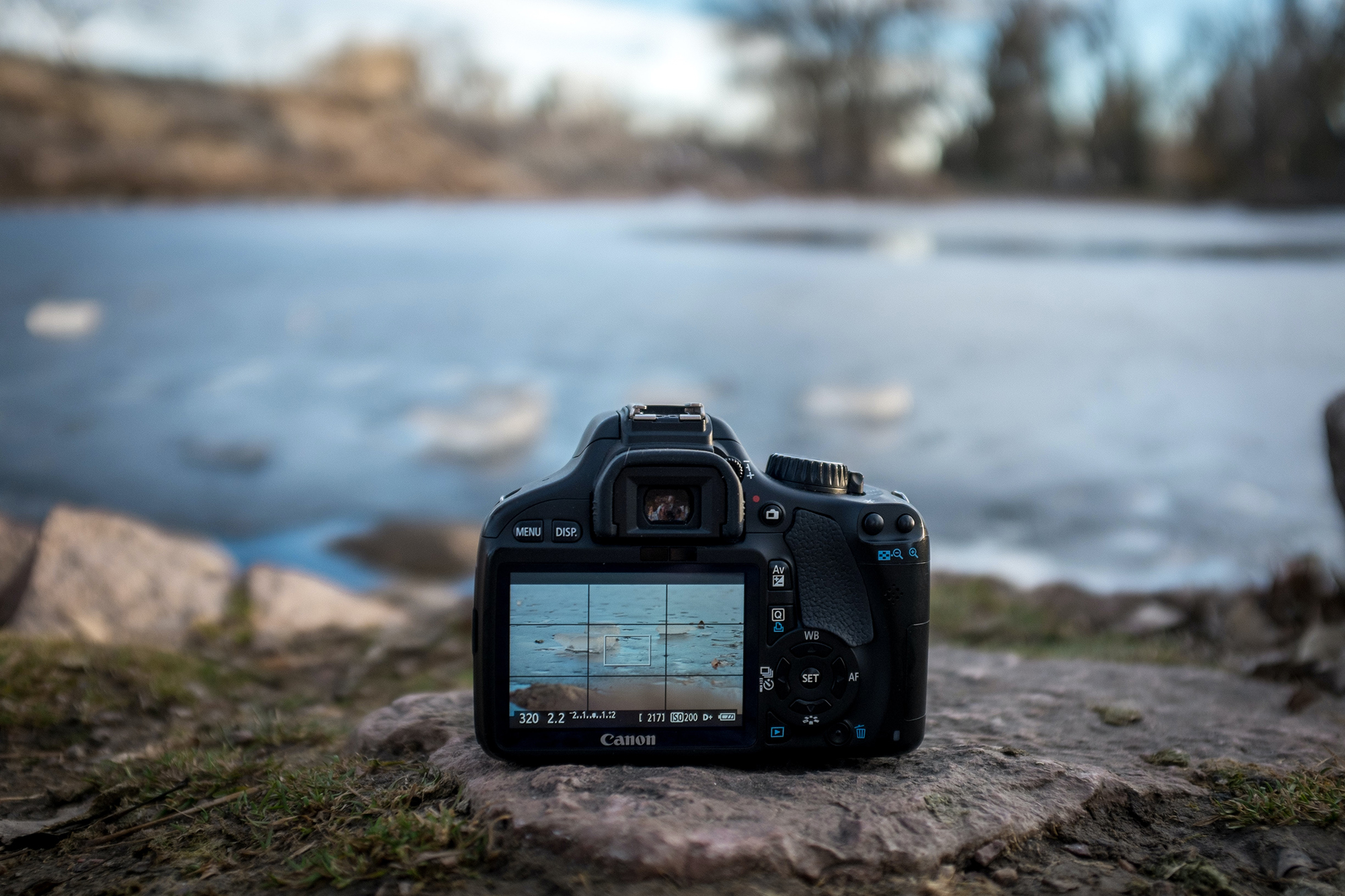 佳能相机放在池塘前的石头上