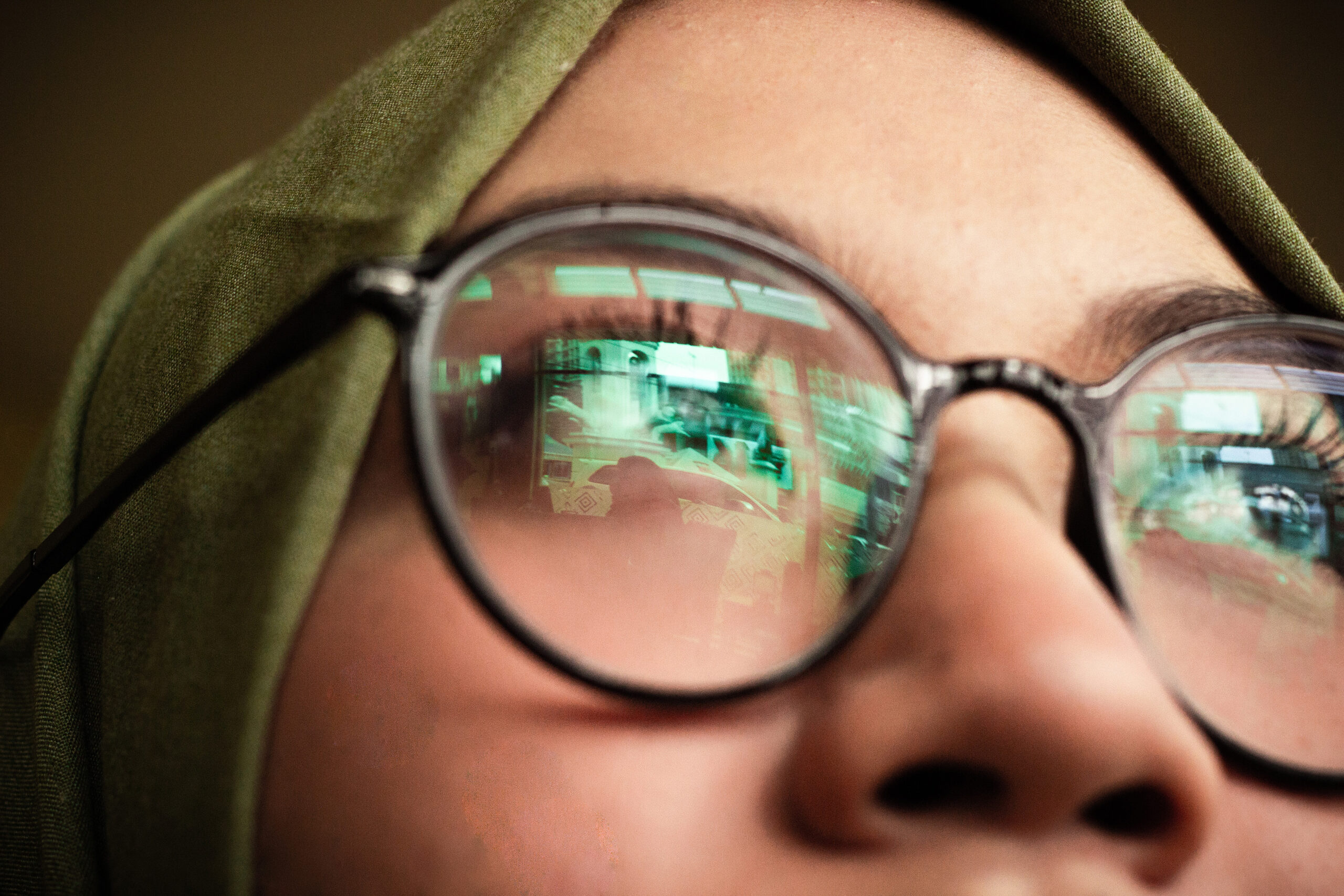 一个戴眼镜的女人，她的镜片里有电脑屏幕的反光。