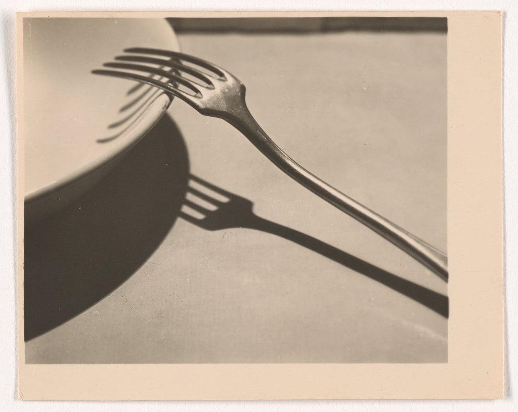 一张B&W照片，叉子放在盘子上，阴影很重。