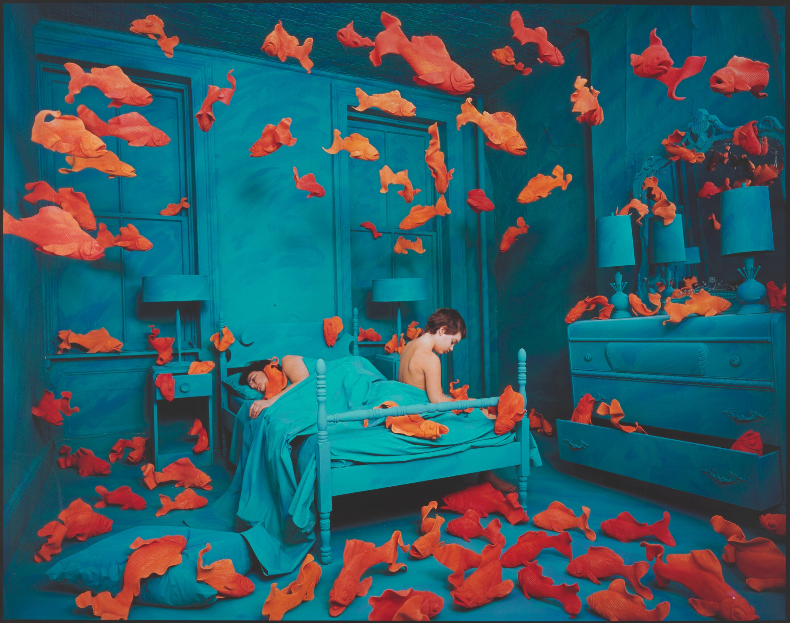 一个孩子在床上被大量的金鱼包围着